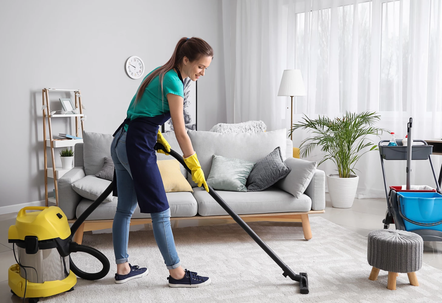 woman from house cleaning company vacuuming a gray carpet
